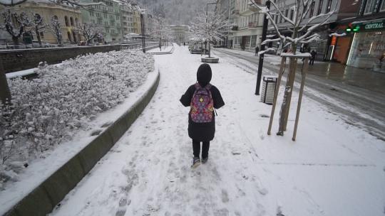 行人在欧洲的小镇雪中行走走路