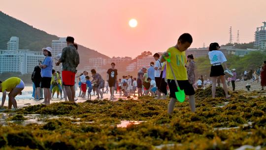 三亚大东海景区沐浴在夕阳余晖下的游客市民