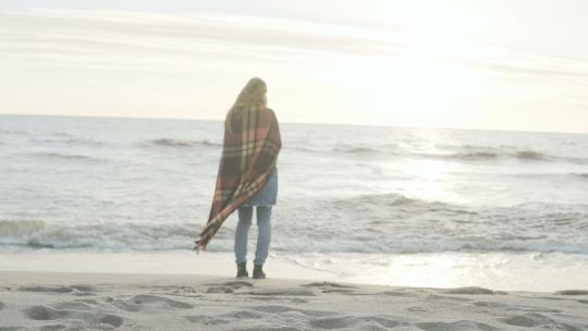 年轻女子站在海边遥望远方的背影。孤独的女性享受海滩。