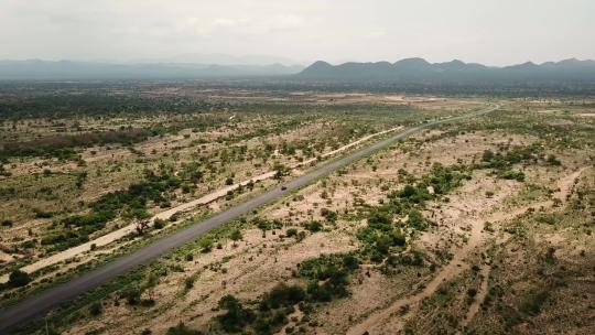 吉普车行驶在埃塞俄比亚广阔平坦的非洲景观上。背景山脉——空中场景