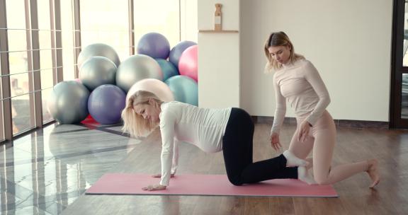 孕妇和她的私人教练做伸展运动