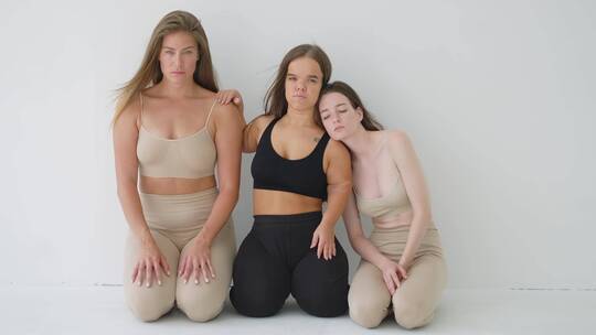 三个穿着运动服的女人跪着看着镜头