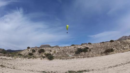 4K滑翔伞运动飞行降落在蓝天白云草地树林间