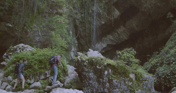 一对夫妇在岩石上徒步走向瀑布