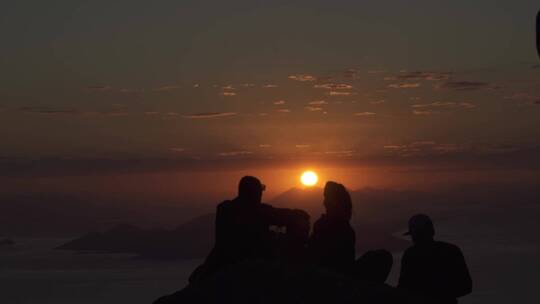 一群人在山顶上拍摄日落景色