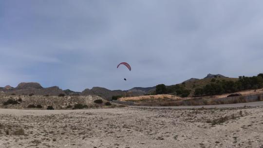 4K滑翔伞运动飞行降落在蓝天白云草地树林间