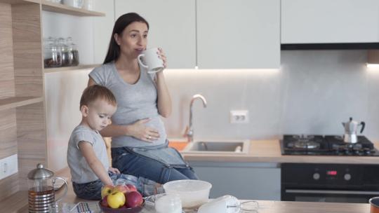 美丽的孕妇站在厨房里喝茶视频素材模板下载