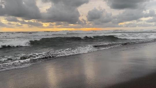 沙质海岸上翻滚的海浪和云景