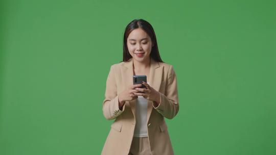 亚洲商务女性使用手机和走在绿屏色度键上