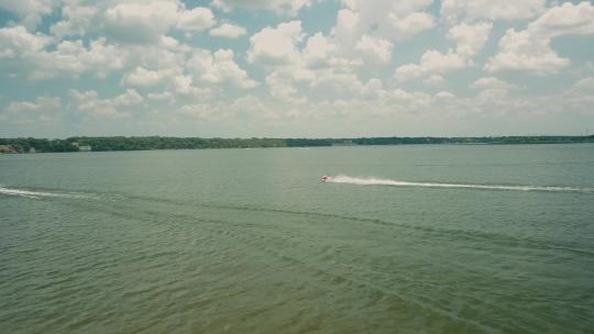 两艘水上摩托车的低空跟随拍摄。中等速度。背景是地平线和树岸。