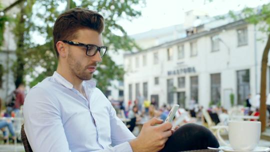 快乐的人在户外咖啡馆放松，在智能手机上浏览互联网