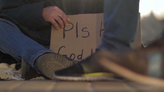 无家可归的人坐在街上乞讨