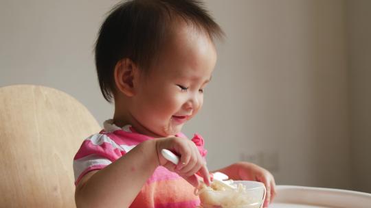 可爱小女孩学用勺子自己吃饭吃面条