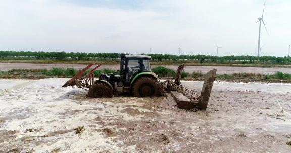 航拍拖拉机在稻田平整土地