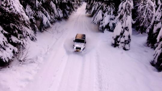 航拍吉普越野汽车行驶在雪景森林雪路中