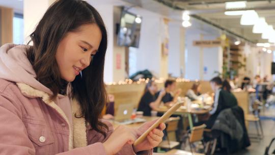 女留学生在学校餐厅使用手机