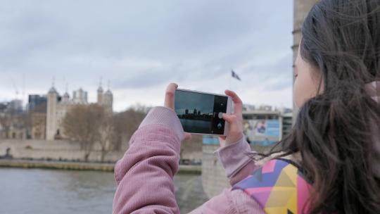 女孩在英国伦敦塔桥旅游用手机拍照