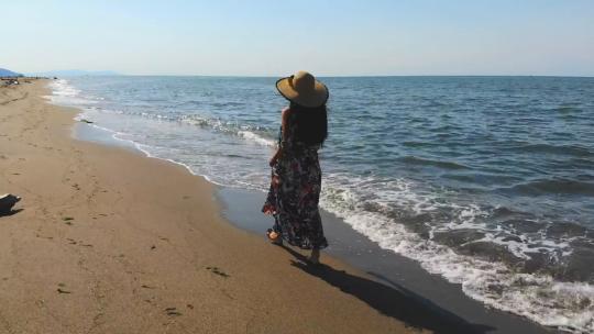 1157_一个戴帽子的女人走在空旷的沙滩上