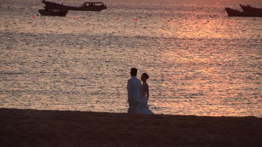 威海西海岸日落湾沙滩上拍摄婚纱照的新人视频素材模板下载