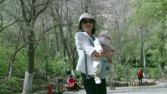 公园中抱着婴儿听着音乐翩翩起舞的女士视频素材模板下载