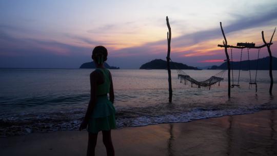 女孩站在日落海滩边