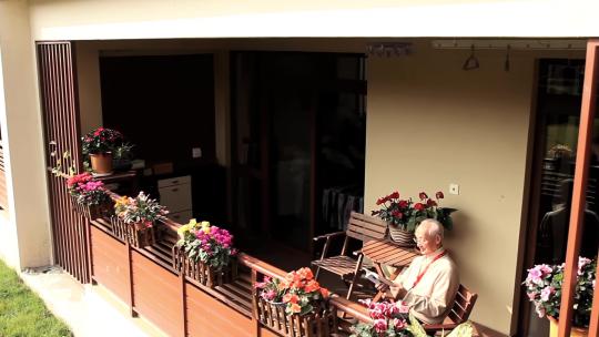 阳台上浇花看报的老人