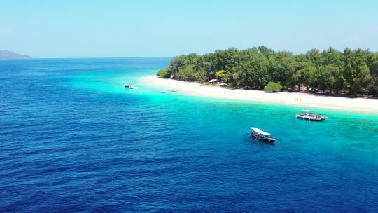 停泊在蓝色绿松石泻湖上的旅游船在白色异国情调的海滩附近等待游客