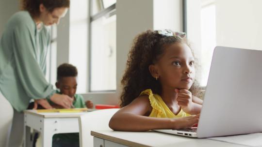 课堂上上课时，专注的非裔美国女孩坐在桌子前拿着笔记本电脑的视频