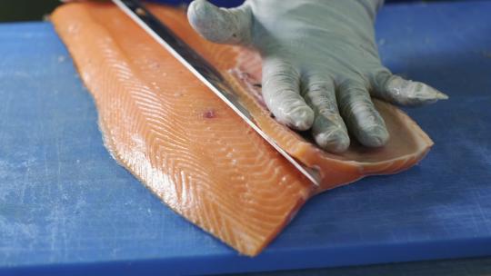红鱼手工切片的过程。厨师用刀把鱼切成块。缓慢的主题