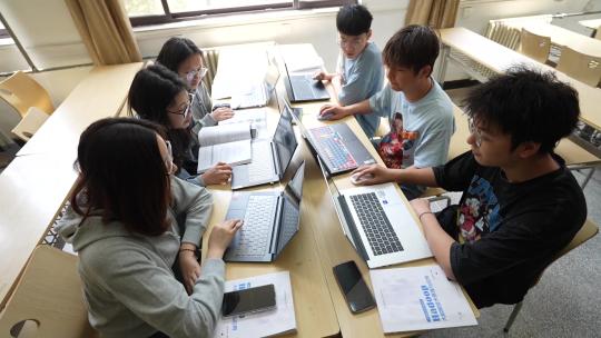大学学校上课学生和同学看电脑交流讨论