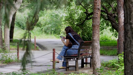 坐在长椅上玩手机的女人