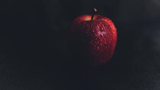 黑背景下有水滴的红苹果特写
