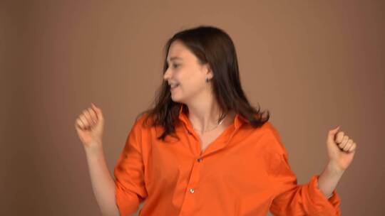 一个穿着橙色衬衫的女人正在快乐地跳舞
