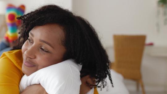 卷发微笑的年轻非裔美国女人在卧室做白日梦