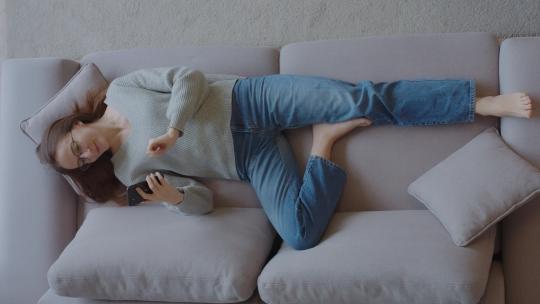 女孩躺在沙发上玩手机