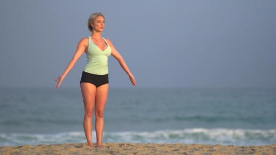 年轻女人在海滩上做瑜伽