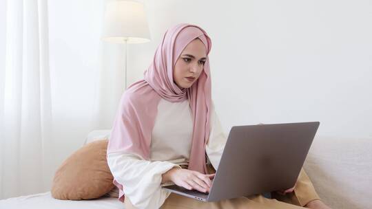 头戴粉色头巾的女人正在用笔记本电脑工作工作