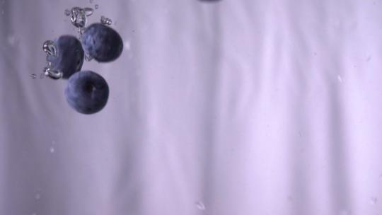 蓝莓掉进白色背景的水中