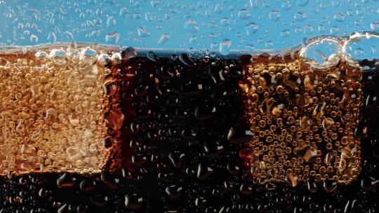 可乐和冰块在玻璃容器中缓慢搅拌的慢镜头