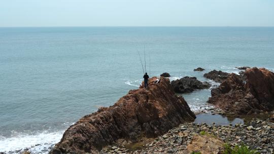 山东青岛海边海滩礁石上钓鱼的人