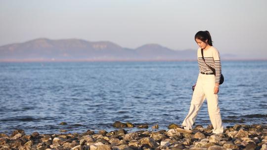 烟台大海黄昏日落，夕阳海边行走的女孩