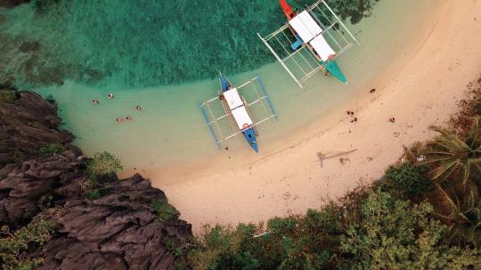 鸟瞰菲律宾巴拉望科隆海滩上的船只和游客4k