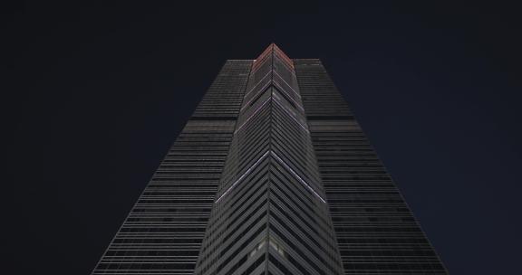 抬头看夜里在办公摩天大楼前行进的镜头。大楼上的led