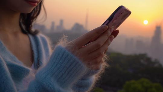 夕阳下玩手机发短信聊天的女性