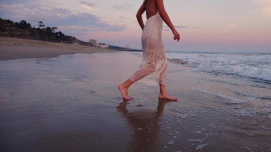 迷人的女人在日落时享受海滩