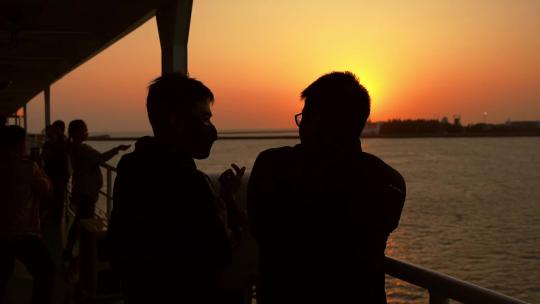 夕阳下在船舷聊天的两名游客