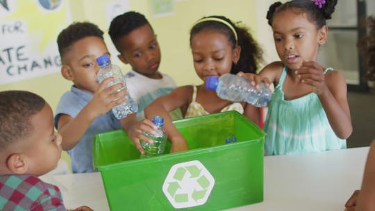 快乐的非裔美国学生在教室里分类回收塑料瓶的视频