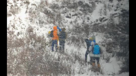 攀登岷山山脉都日峰的登山者在雪中徒步行进