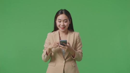 在绿屏上女人使用智能手机庆祝