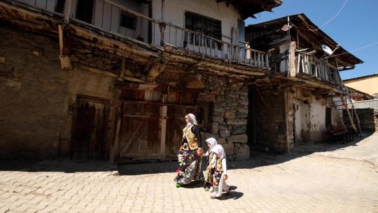 中穿着传统土耳其服装的妇女和他们的孩子走在乡村街道上